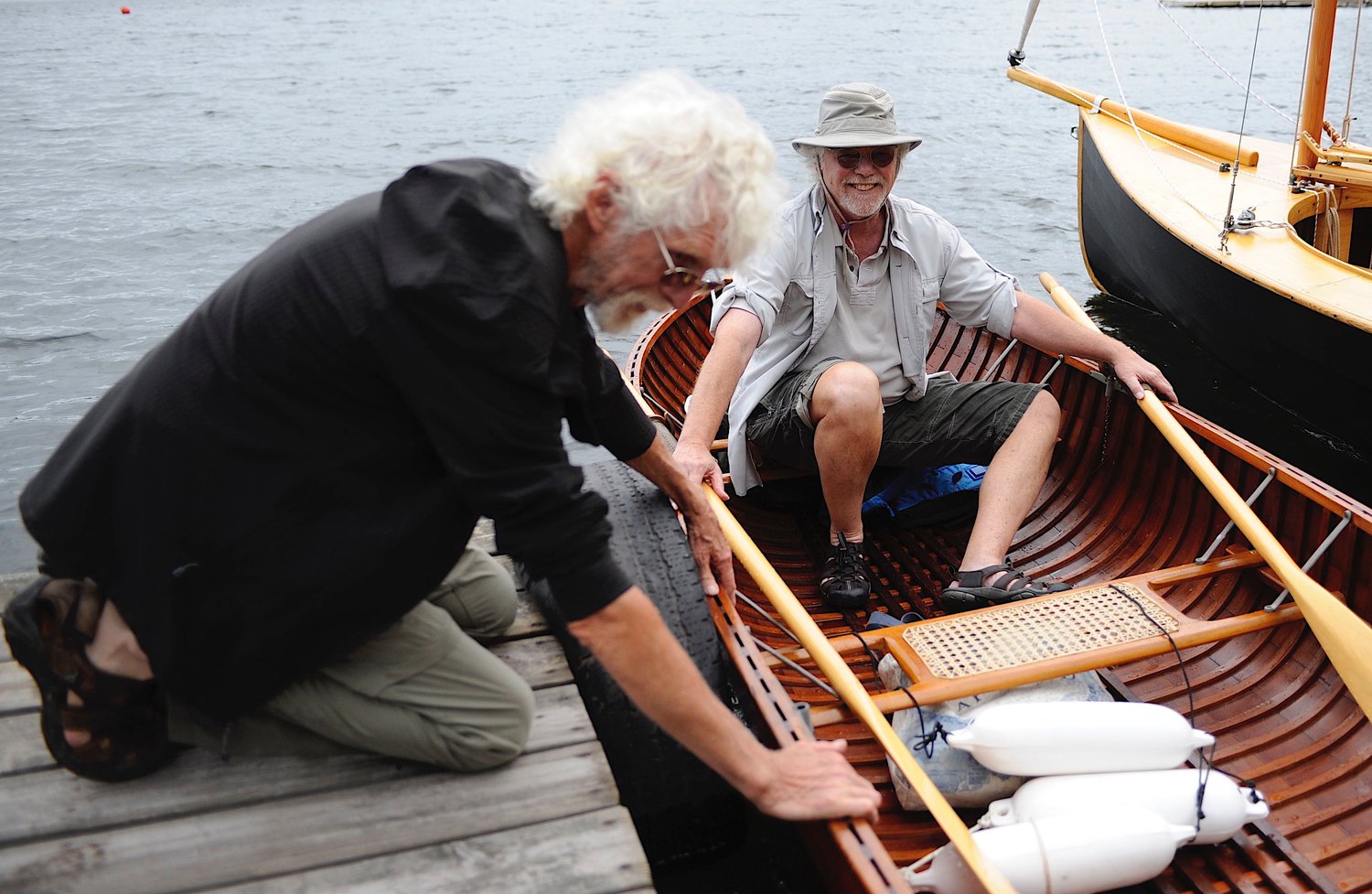Founder’s afternoon at the dock. Zeke Boyle lends a hand to co-founder Joe Freda as the latter disembarks from the 1938 Penn Yan rowboat.